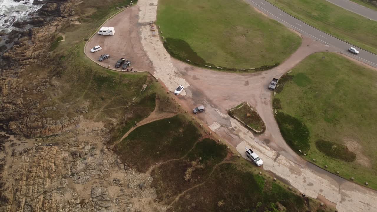 surfer lleva tabla de surf mientras camina hacia la playa rocosa