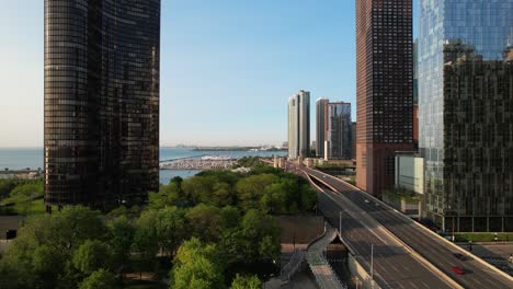 cars traveling on high way next to lake with city highrises