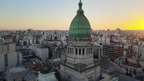 aerial flying above argentine congress palace green bronze dome surrounded by buenos aires buildings at golden hour