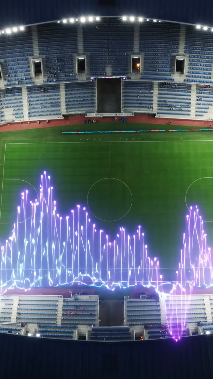 Vertical video: Pulsing waveform reacting to sound along lower stands over football pitch and track