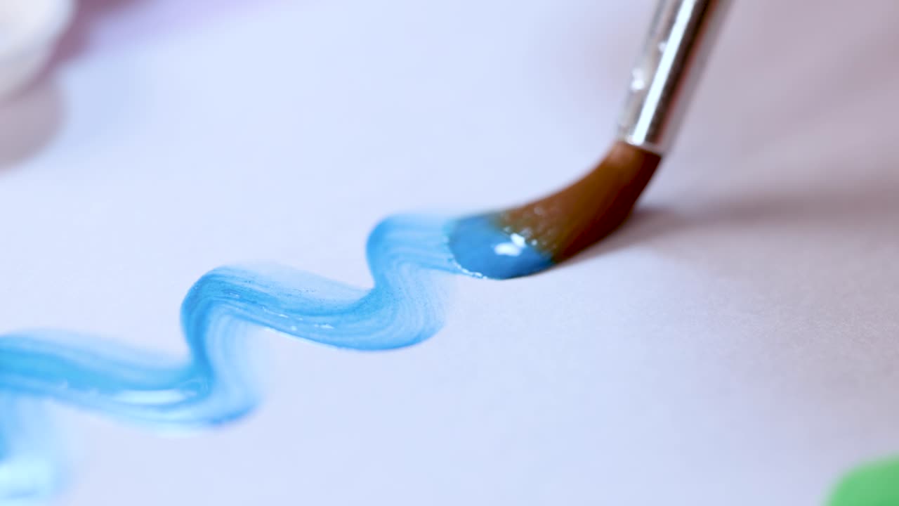 Paintbrush draws blue watercolor zigzag on white paper, soft natural lighting, macro perspective