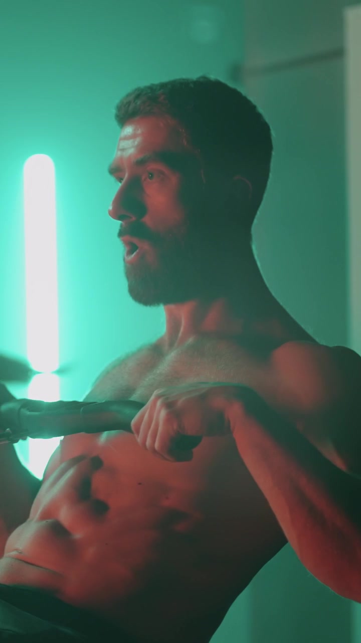 Uomo e donna atletici si allenano sui vogatori in una palestra illuminata al neon