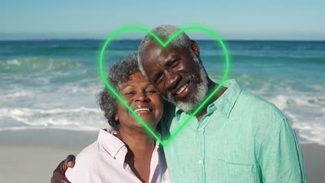 Animation-of-green-hearts-over-african-american-senior-couple-on-the-beach