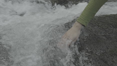 person touching water in a stream