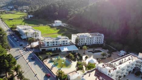 Drone-shot-of-some-houses-with-a-green-pool-on-Ibiza