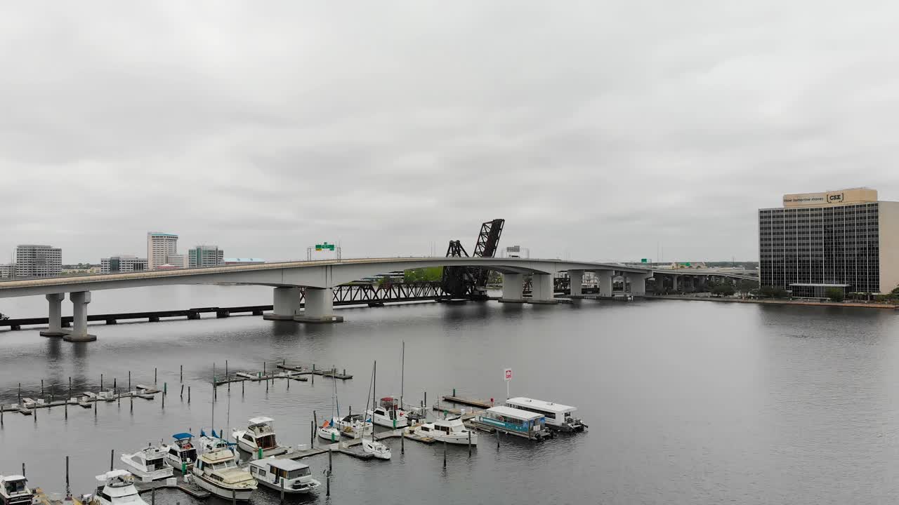 barcos alineados en fila a lo largo del río con el puente blanco visible en el fondo