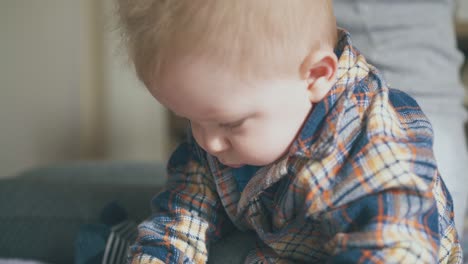 funny-boy-in-warm-shirt-plays-with-spoon-at-mother-on-bed