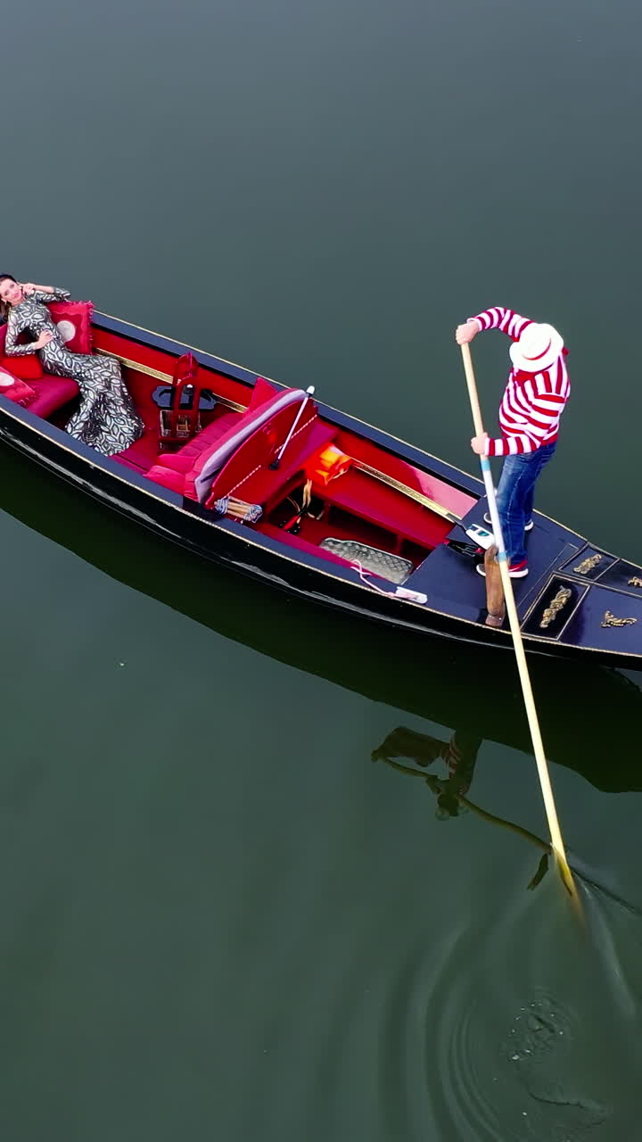 Gondolier putting gondola through river. Aerial view of gondolier carries tourists on gondola