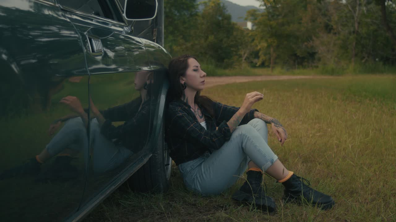 Woman Sitting Beside a Car in a Natural Setting