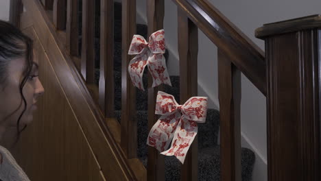 Female-Teenager-Sticking-Double-Christmas-Bows-With-Snowman-Design-On-Stair-Spindles