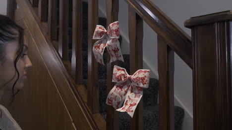 female teenager sticking double christmas bows with snowman design on stair spindles