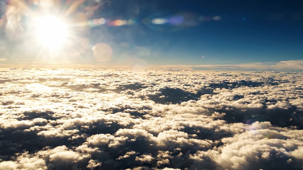 Breathtaking Aerial View of Puffy Clouds Glowing Under the Sun, Captured from Above with a Serene Blue Sky as the Backdrop in Fantastic Natural Light