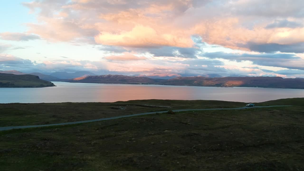 Golden hour panning drone shot of Scottish mountain lake