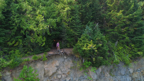 female hiker standing on cliff in forest 4k