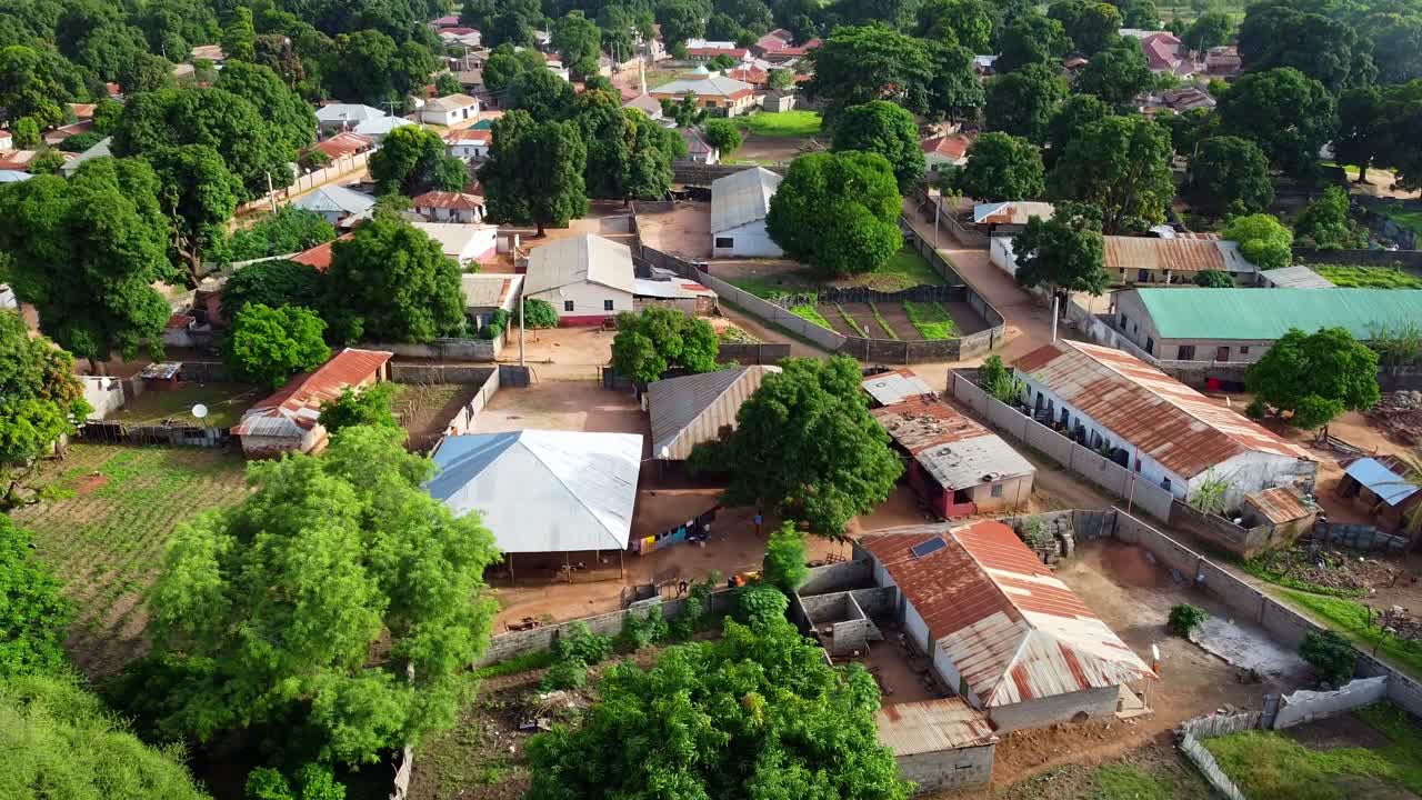 Aerial reverse shot of local houses in Nuimi Lameng African rural village in The Gambia
