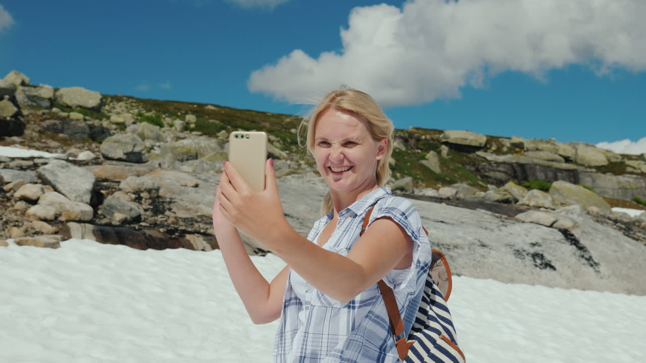 una mujer feliz haciendo selfie en un glaciar en noruega hace calor pero la nieve aún no se ha derretido la mañana
