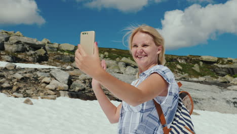 una mujer feliz haciendo selfie en un glaciar en noruega hace calor pero la nieve aún no se ha derretido la mañana