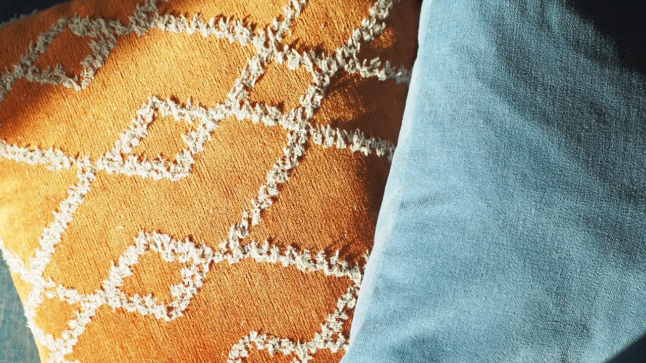 cerca de dos almohadas - una es naranja con patrón geométrico y la otra es azul