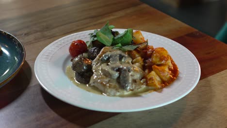 delicious chicken dish recipe with mushroom cream, potatoes and salad on a restaurant table