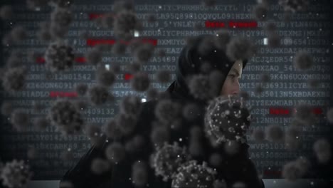 animation of of macro covid19 cells over man wearing hoodie, using a laptop