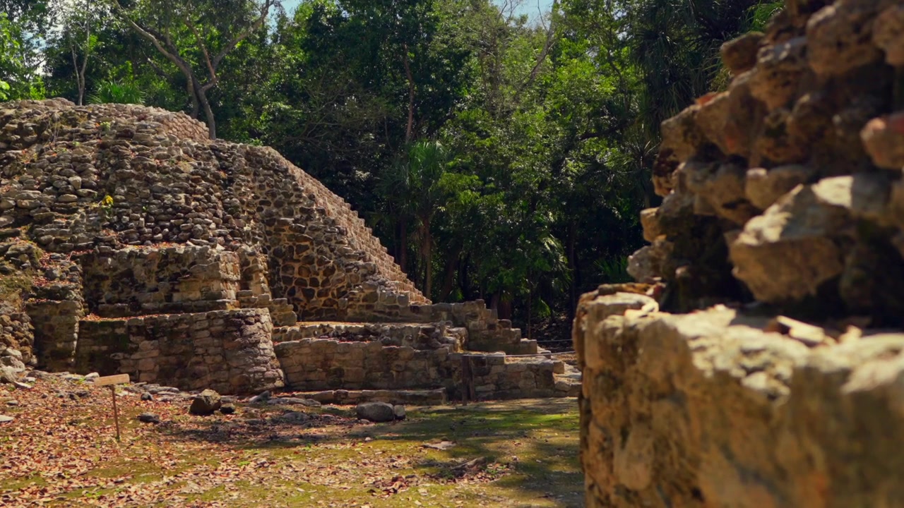 Camminando attraverso la giungla lussureggiante che circonda le antiche piramidi Maya di Oxtankah in una splendida giornata di sole in Quintana Roo, Messico.