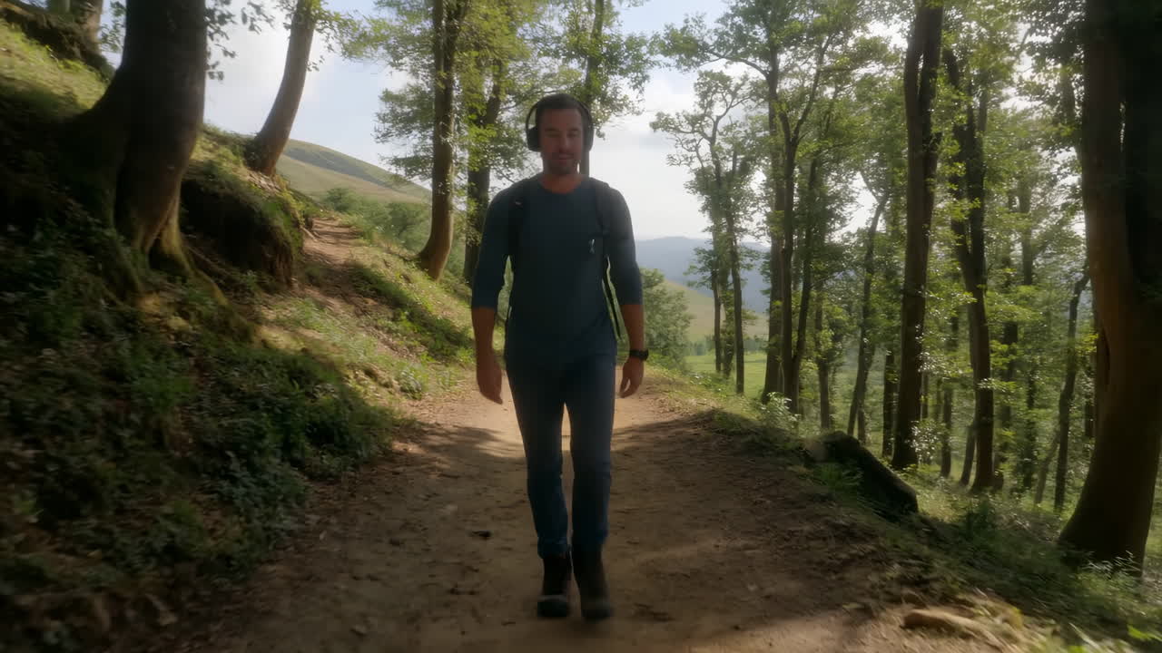 Uomo con le cuffie cammina lungo un sentiero sterrato nel bosco.