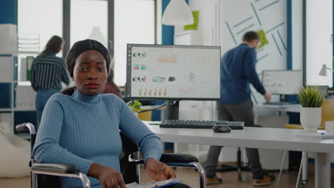 black woman with disabilities looking at camera sitting in business office