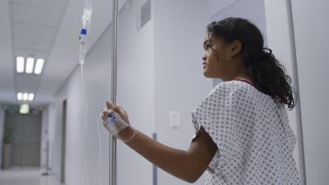 Mixed-race-girl-walking-with-drip-bag-in-hospital-room