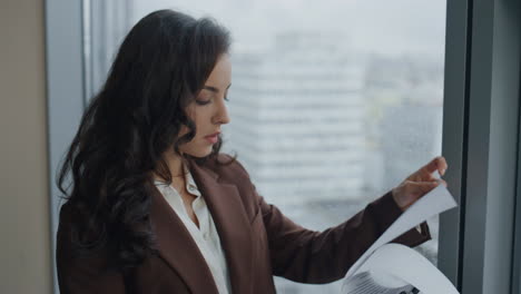 mujer ceo leyendo documentos contrato de negocios de pie en la ventana de la oficina de cerca