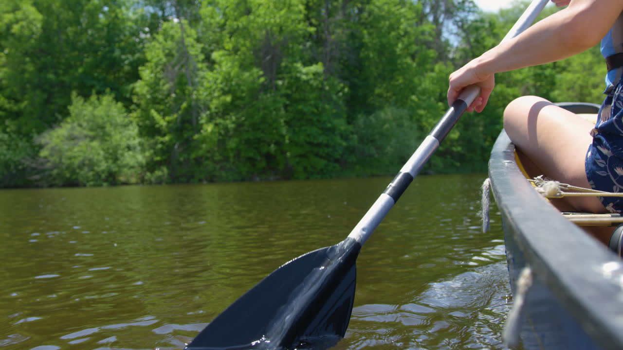 mujer remando una canoa por un hermoso río rodeado de frondosos árboles
