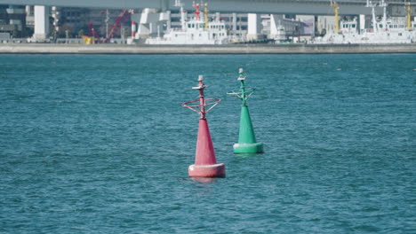 a slow motion shot of a red and a green buoys floating in tokyo bay, japan