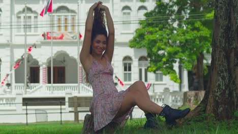 latina smiles and playing in her hair while sitting on a log in a mini skirt and boots