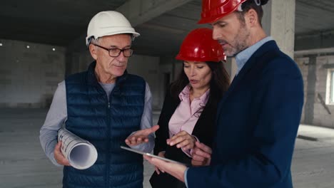 medianas imágenes de un grupo de ingenieros caucásicos e inversores de pie y discutiendo en el sitio de construcción.