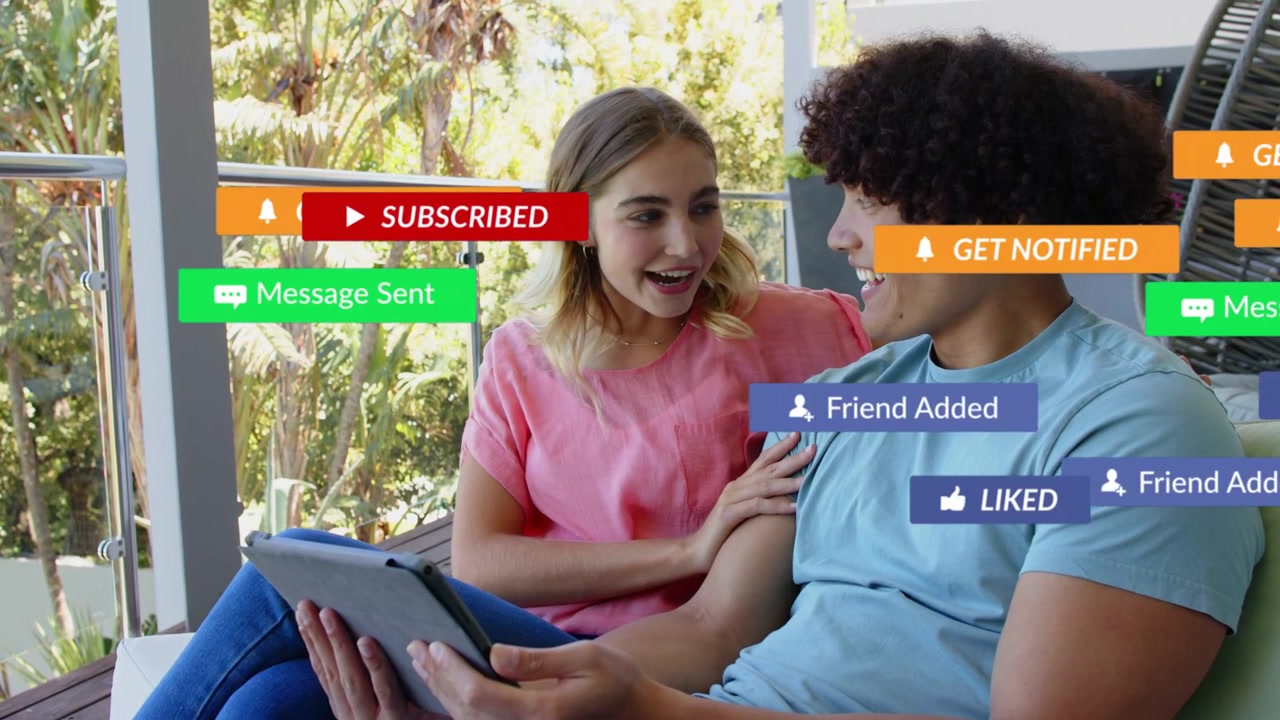 Couple holding tablet on porch tapping play and reacting as animated social badges appearing