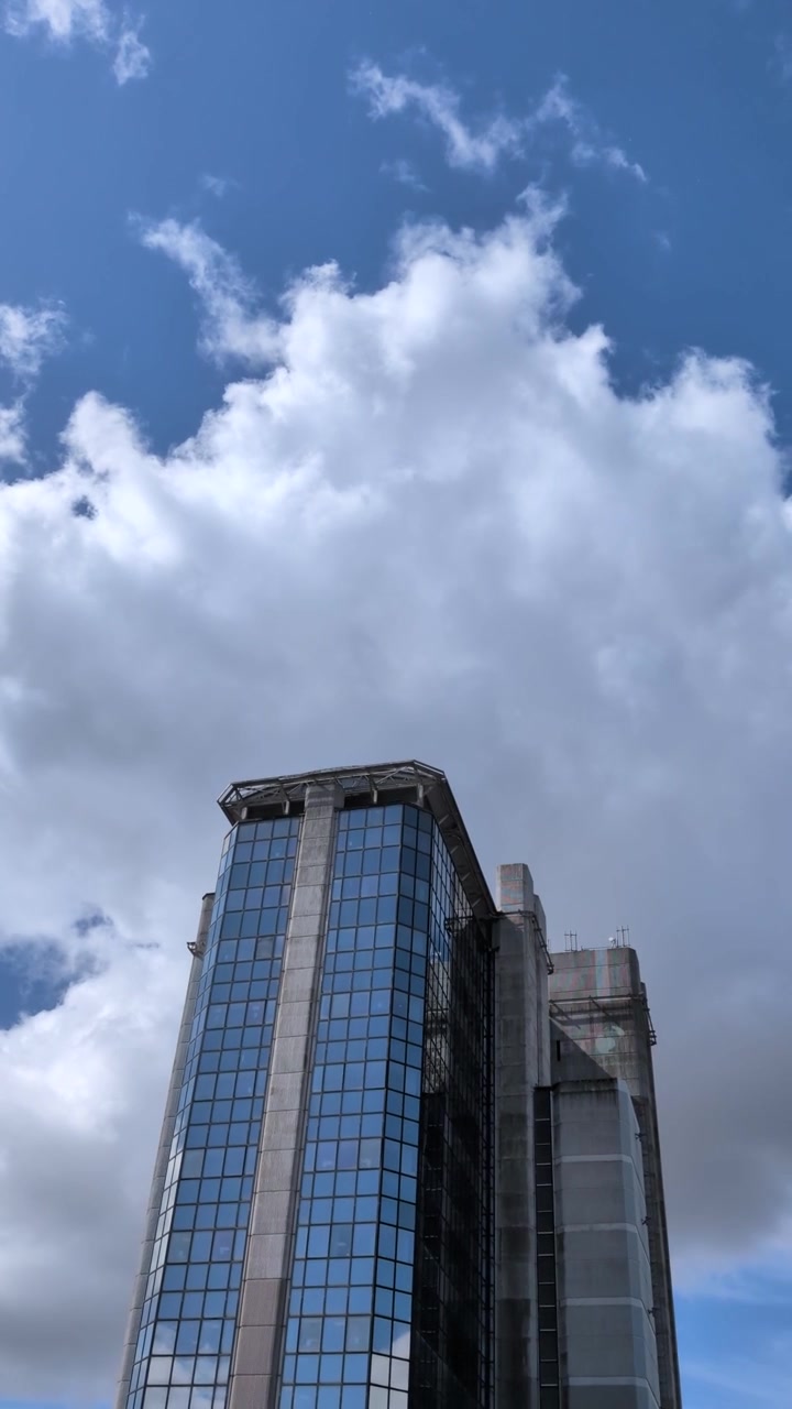 Video vertical de un edificio corporativo alto contra un fondo de cielo azul con espacio para texto en la parte superior.