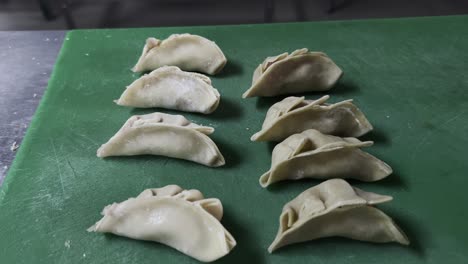 raw gyoza dumplings neatly placed on green board, ready to be cooked or steamed