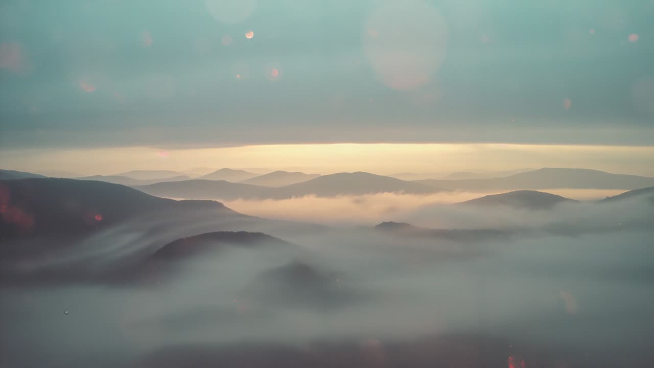 Sunrise lifting mist revealing ridges at valley dawn, showing lens flare and conifer silhouette