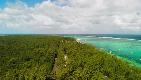 green trees of mauritius island and boats parked on water at le morne beach under white clouds