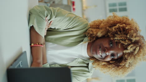 portrait of smiling black woman sitting with laptop at home