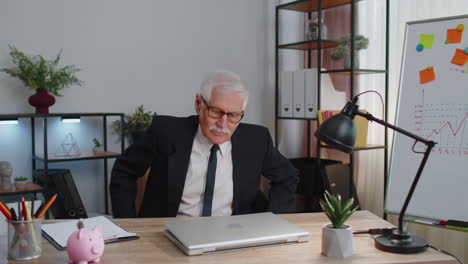 smiling mature business man sits at workplace office desk, opening laptop computer, start working