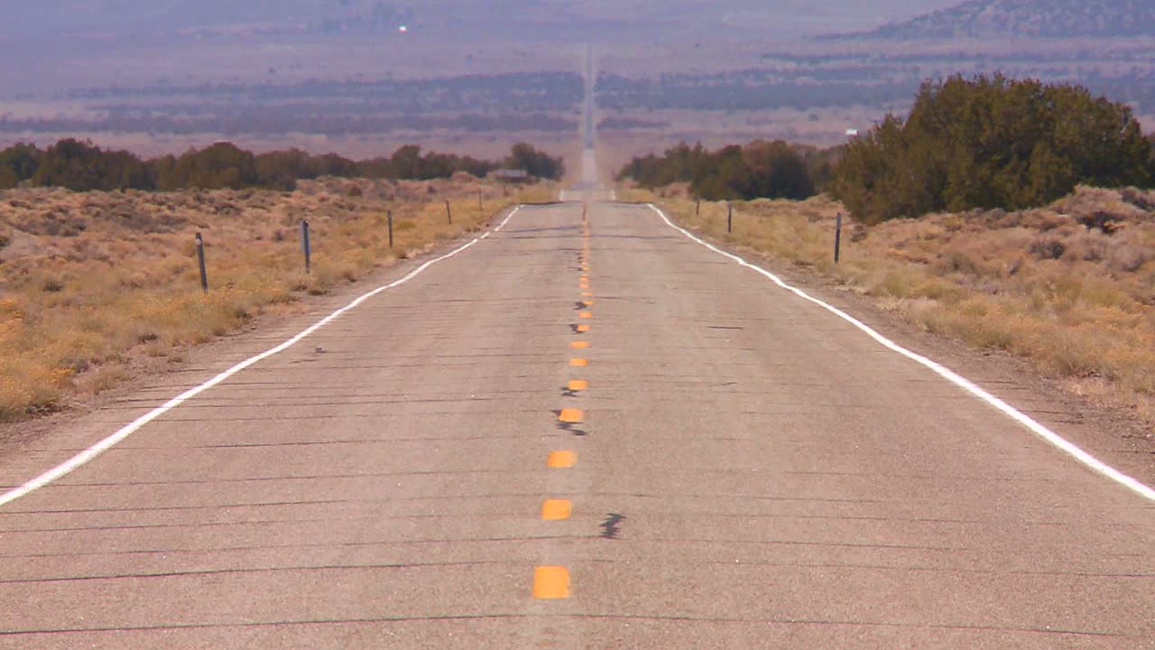 el calor se eleva desde un largo camino recto y solitario en el desierto