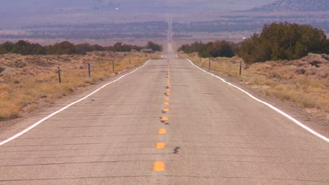 el calor se eleva desde un largo camino recto y solitario en el desierto