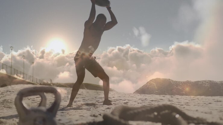 Animation of clouds over african american man weight training on beach