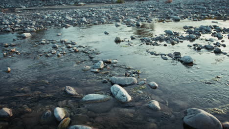 slow stream flowing water between river rocks in relaxing peaceful nature