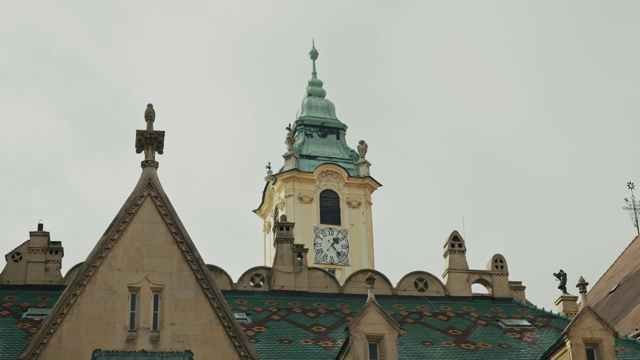 Ornate clock tower with green spire and colorful tiled roof in Bratislava Old Town