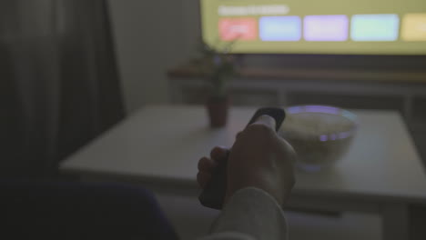 someone's hand with a remote control navigates through the tv menu for a programme or film to watch 2