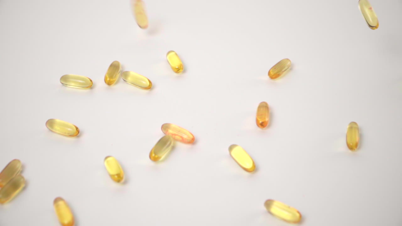 cámara lenta de pastillas amarillas caídas sobre fondo blanco