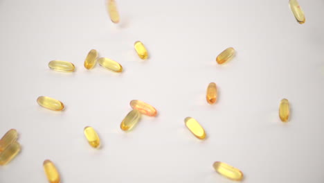 slow motion of yellow pills dropped onto white background