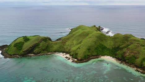 green mountain hills of bukit merese in lombok surrounded by turquoise water, aerial