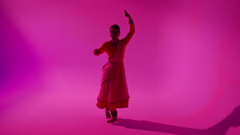 camera moves through studio equipment to show female kathak dancer wearing traditional indian dress dancing 1